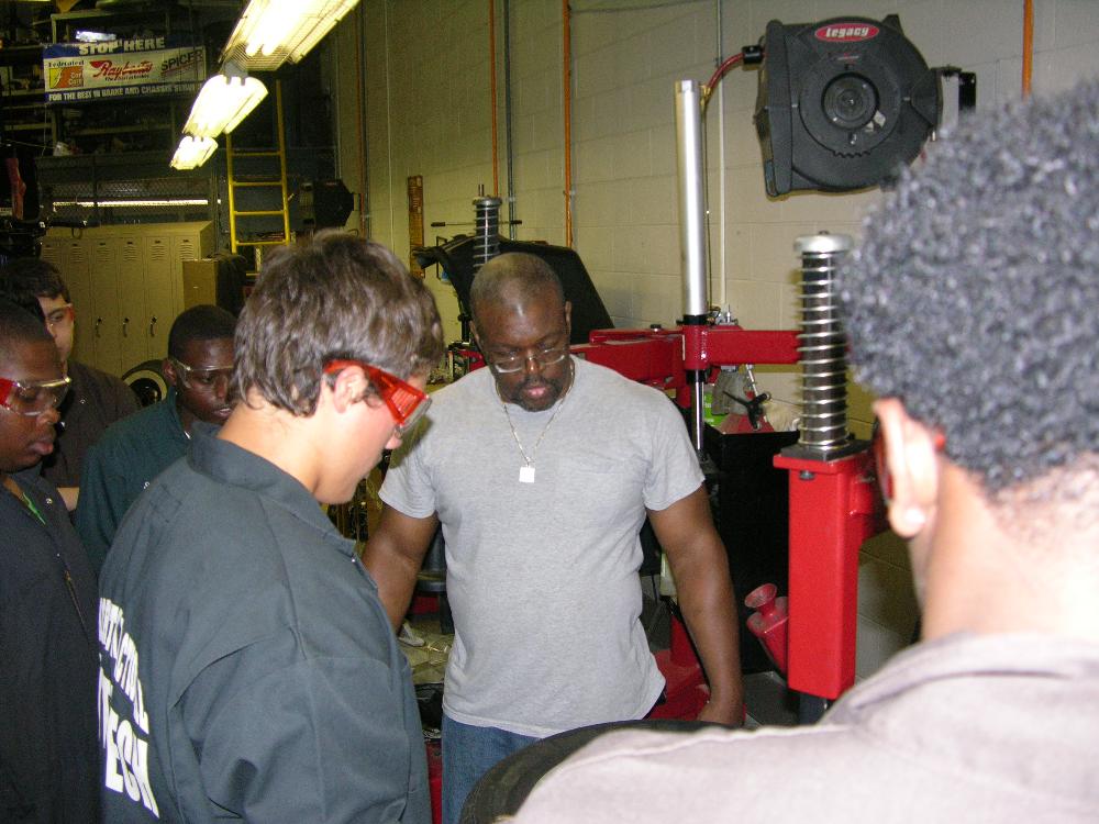 Mr. Reilly supervising Auto Tech I students repair a tire